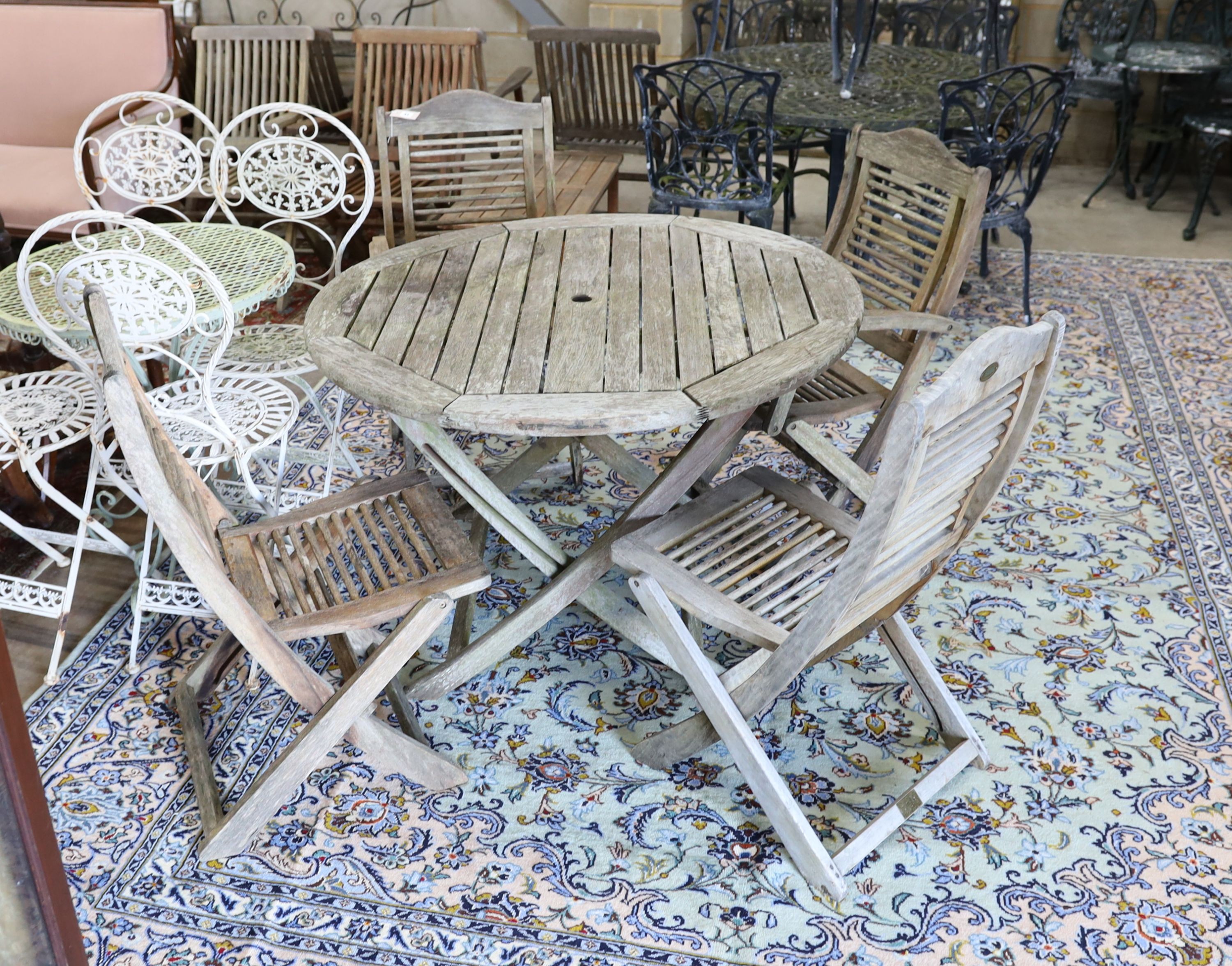 A weathered teak circular folding garden table, diameter 110cm, height 74cm and four folding chairs